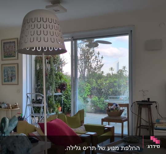 סלון דירה עם חלון הזזה זכוכית גדול היציאה למרפסת